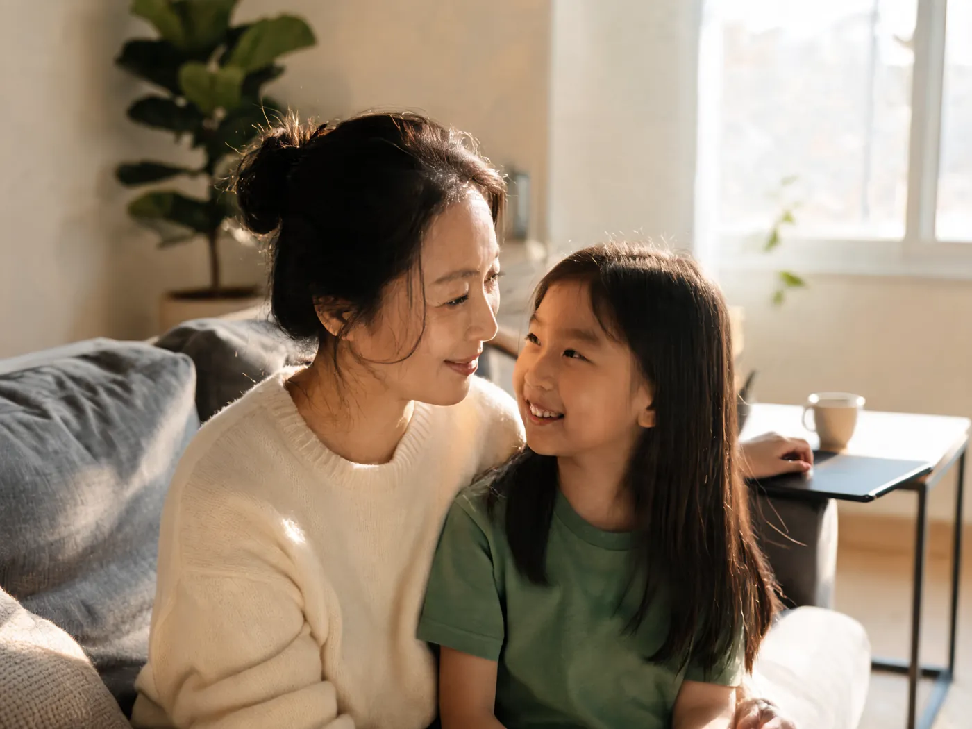 A mother and her daughter smiling warmly at each other on the couch